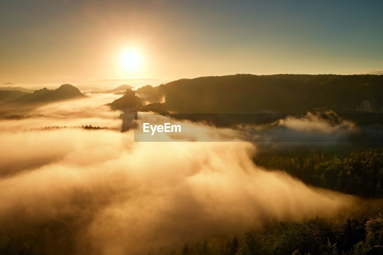 Fantastic colorful sunrise on the top of the rocky mountain with the view into misty valley