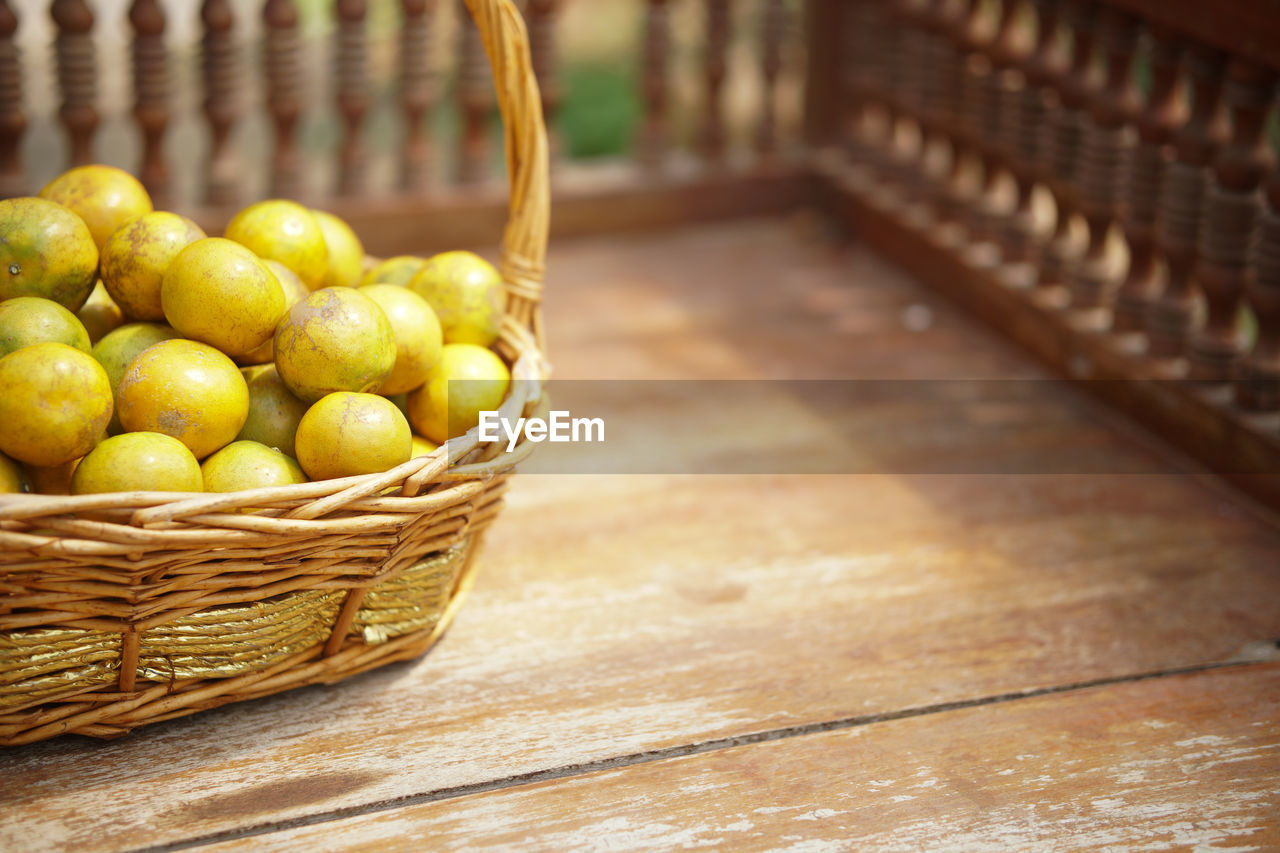 Fresh orange tangerine fruit in rattan wicker basket on wooden chair