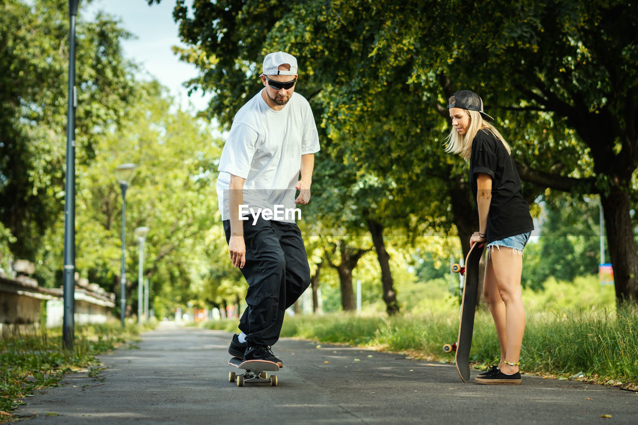 Couple with skateboards on footpath at park