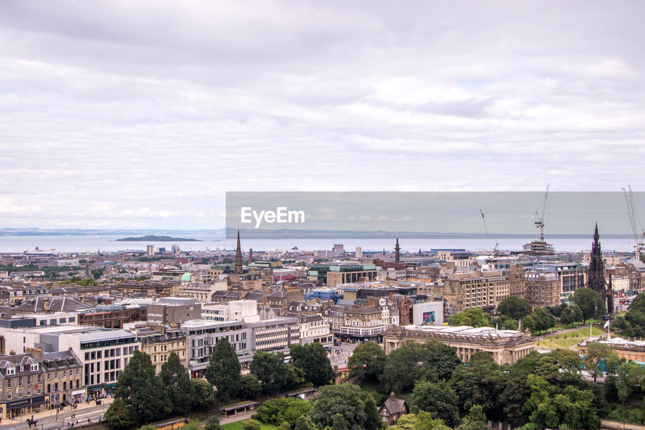 HIGH ANGLE VIEW OF CITY BUILDINGS AGAINST CLOUDY SKY