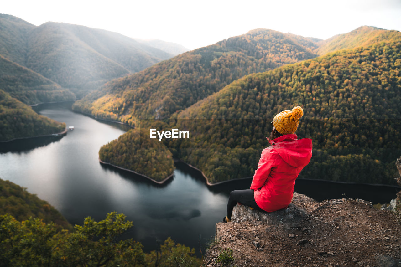 rear view of woman looking at lake against mountain