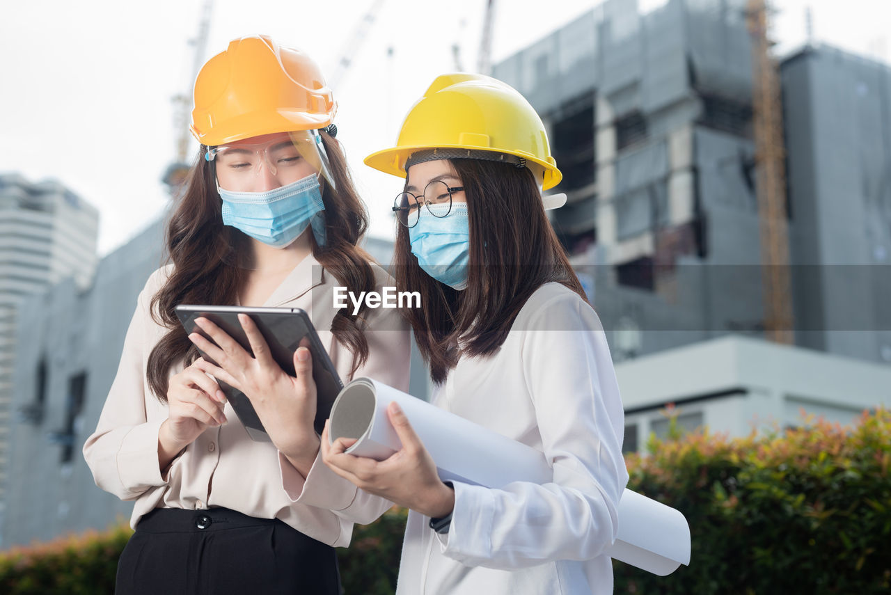 WOMAN HOLDING MOBILE PHONE WHILE STANDING ON LAPTOP IN SMART