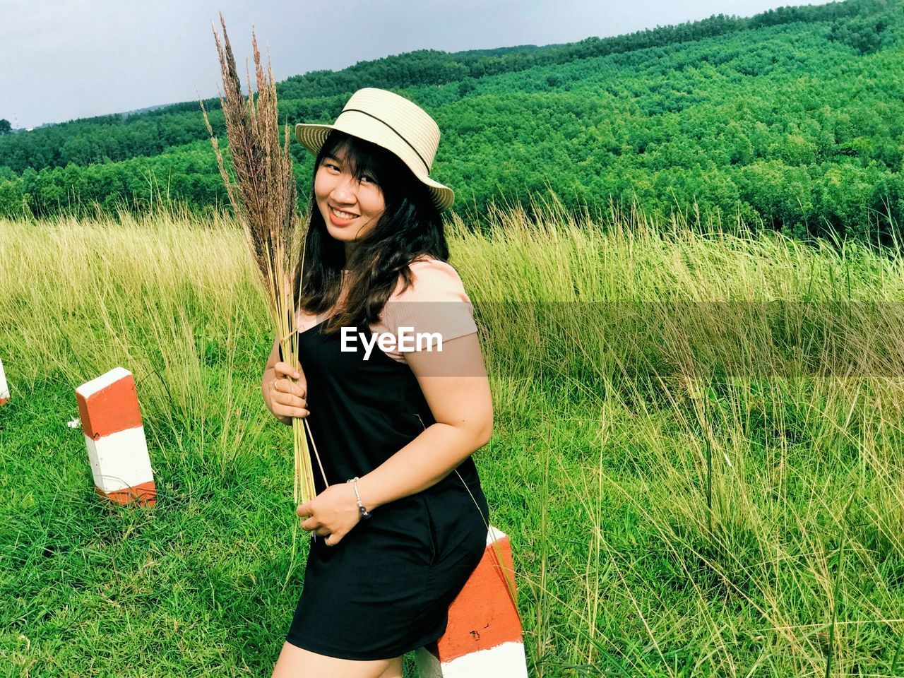 Portrait of smiling young woman standing on field