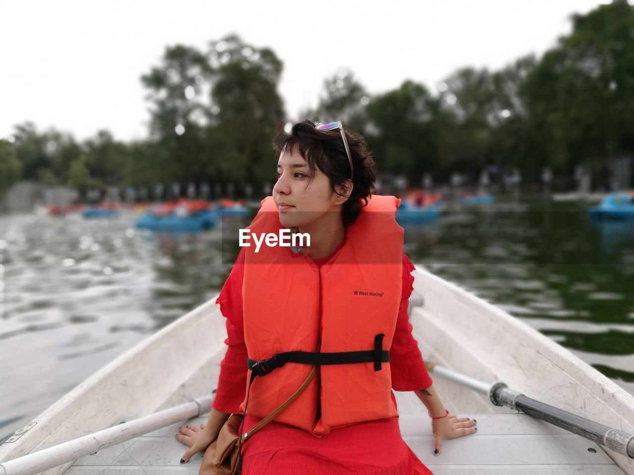 Woman wearing red life jacket while traveling on boat at lake