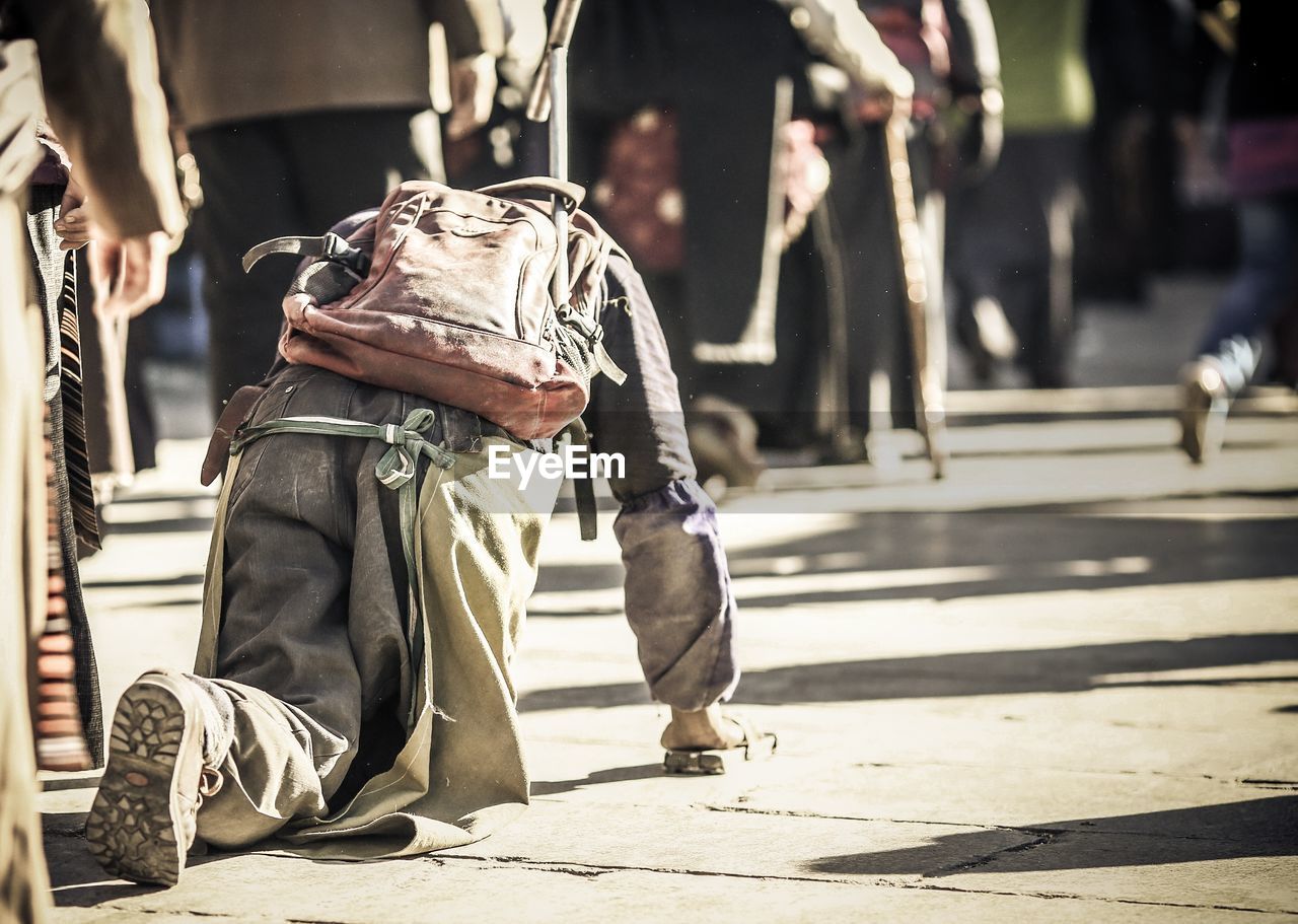 Rear view of disabled man crawling on footpath