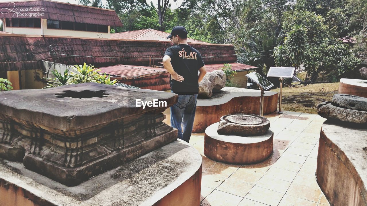 REAR VIEW OF MAN STANDING OUTSIDE TEMPLE