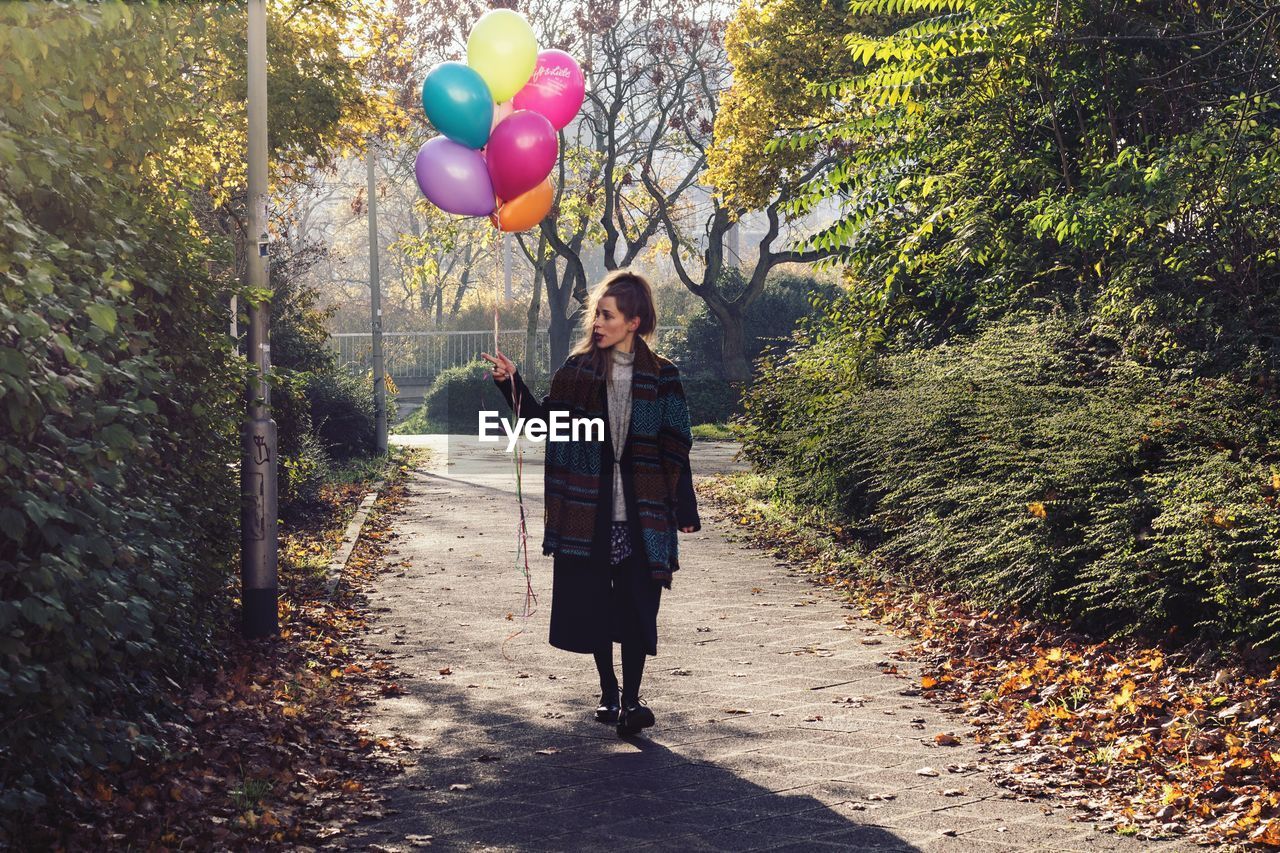 Full length of young woman walking with balloons at park