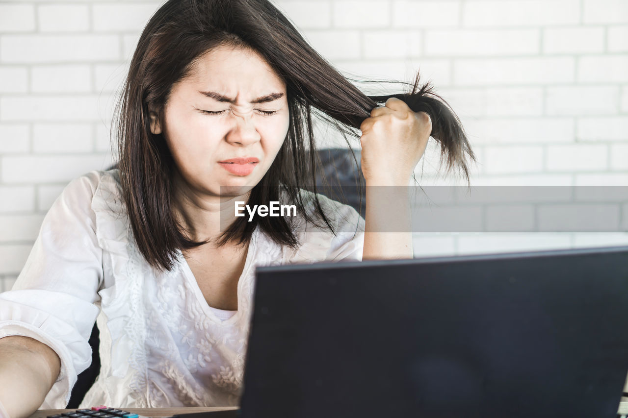 Frustrated businesswoman pulling hair while sitting in office