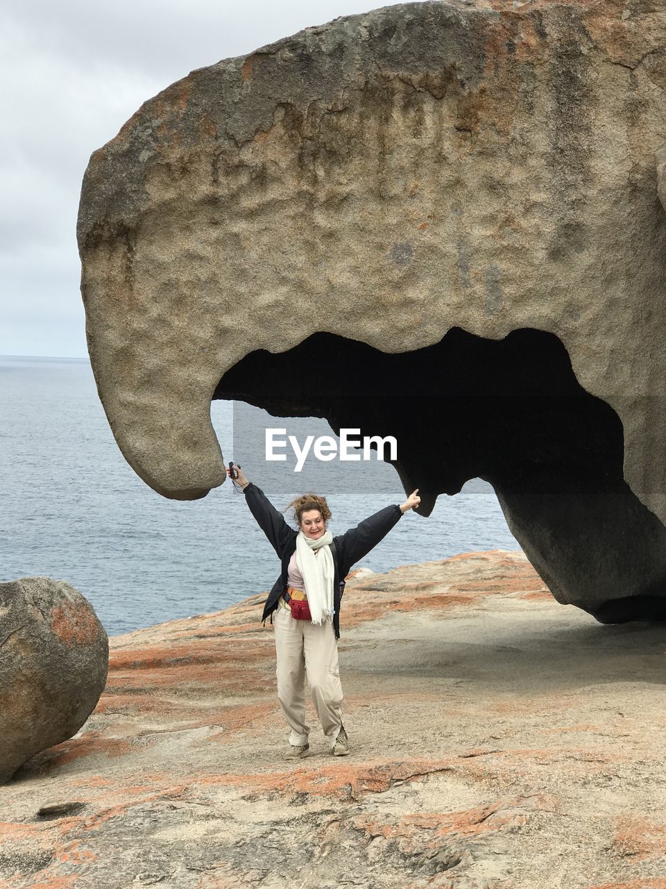 Full length of cheerful woman standing against rock formation