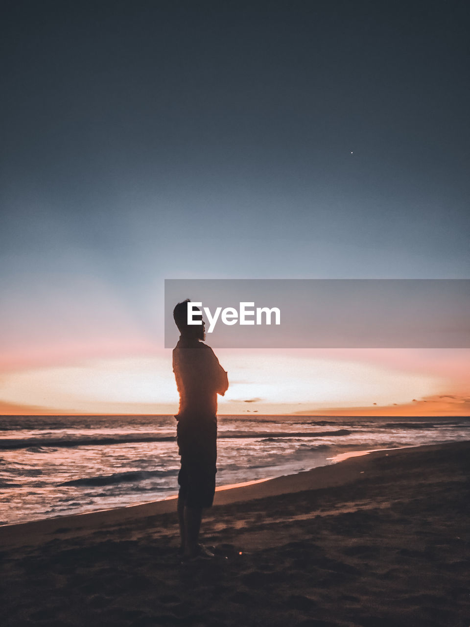 Silhouette man standing on beach against sky during sunset