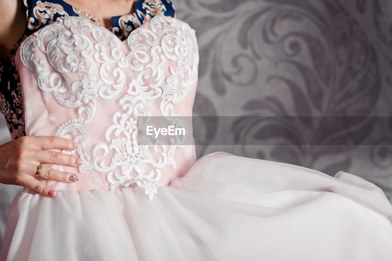 Midsection of tailor holding wedding dress