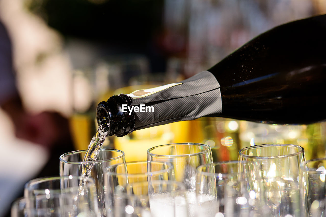 Closeup of serving champagne  in a group of champagne flutes with a colourfull background.