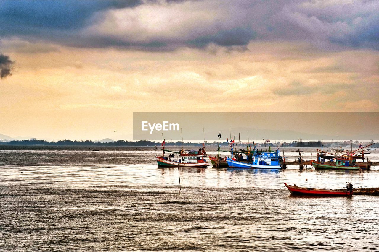 BOATS SAILING IN CALM SEA AGAINST CLOUDY SKY