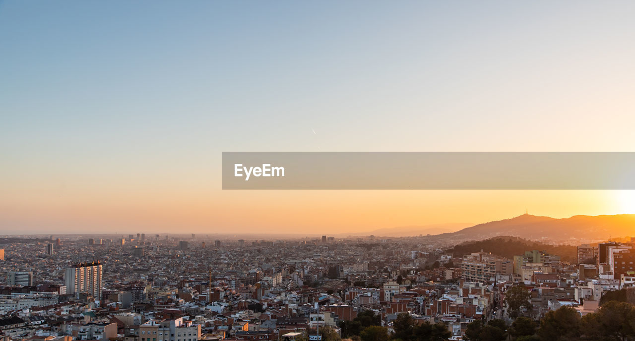 HIGH ANGLE SHOT OF TOWNSCAPE AGAINST SKY AT SUNSET