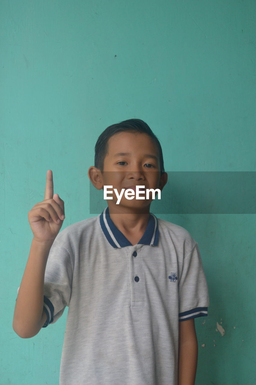 one person, child, childhood, smiling, blue, men, portrait, happiness, indoors, looking at camera, emotion, hand, arm, person, copy space, lifestyles, baby, casual clothing, fun, human head, toddler, colored background, clothing, human mouth, cheerful, human face, high angle view, leisure activity, waist up, positive emotion, cute, relaxation