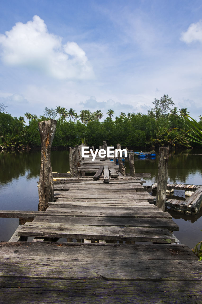 WOODEN PIER ON LAKE BY TREES AGAINST SKY