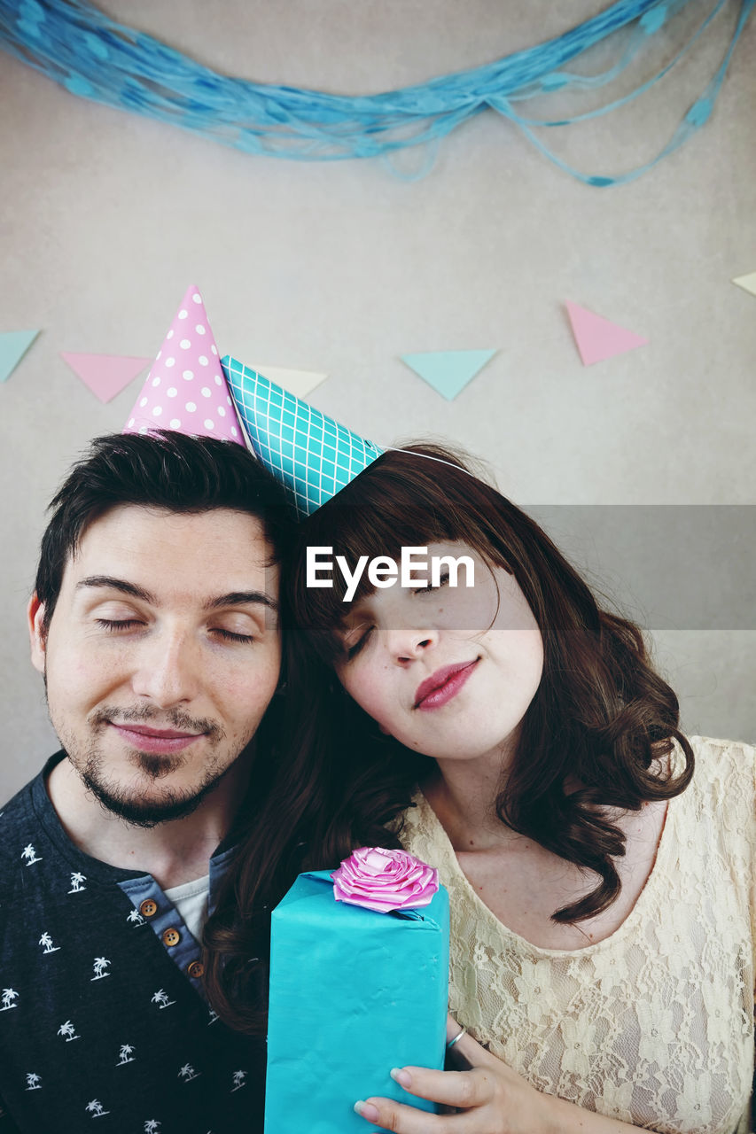 Close-up of couple with gift box against wall during birthday