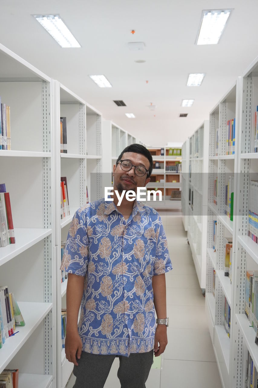 Portrait of smiling man standing at library