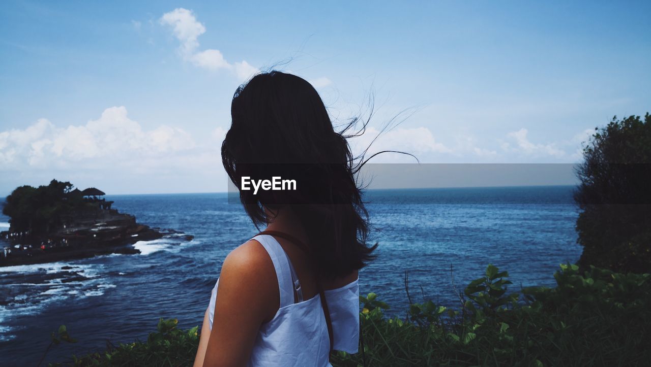 Woman standing by sea against sky