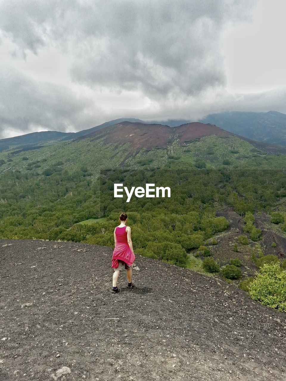 Rear view of woman walking on cliff in front of mountains