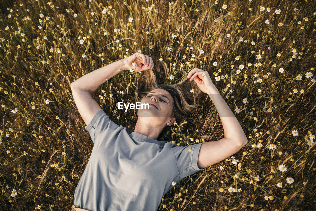 Woman with hands in hair lying on field