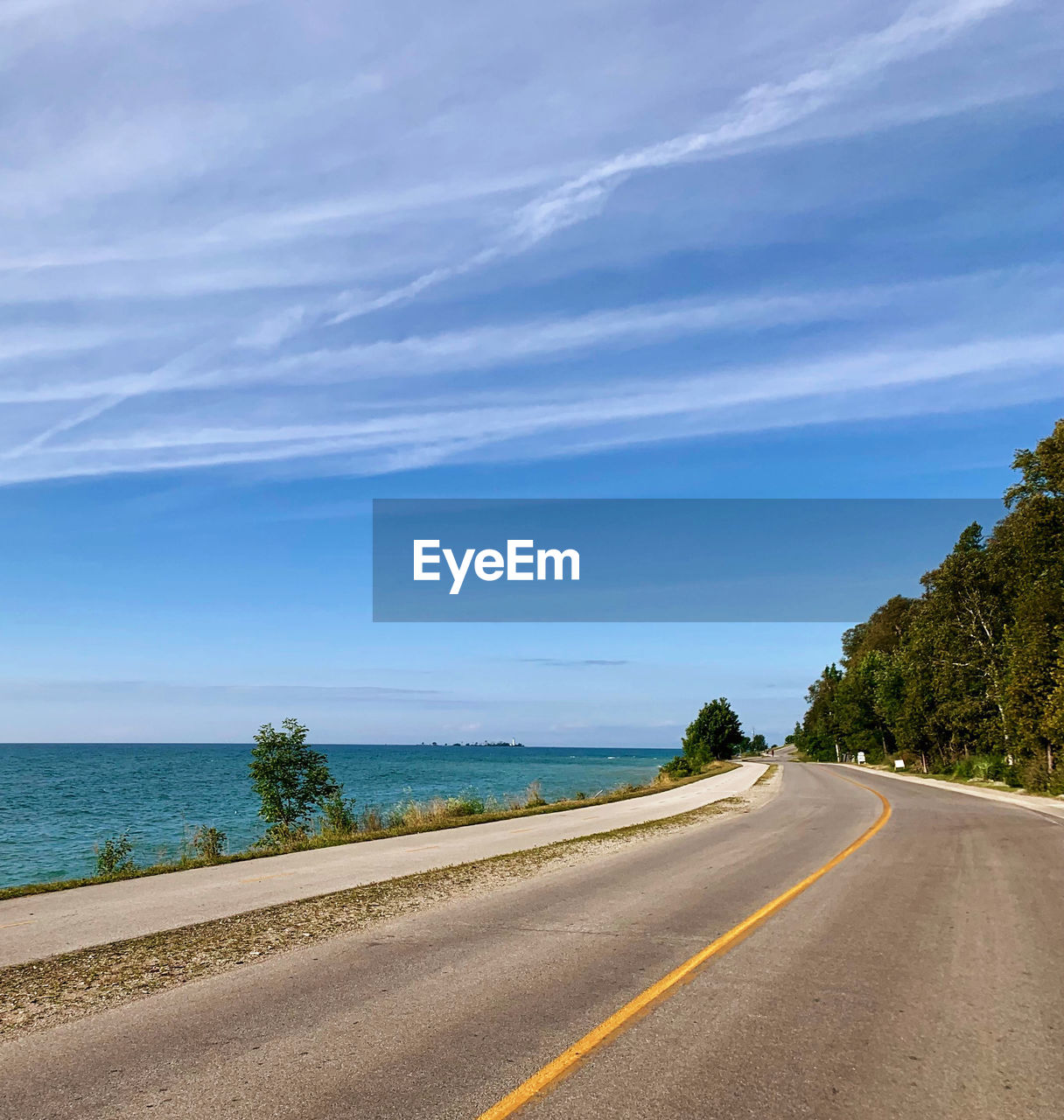 Road by lake against blue sky