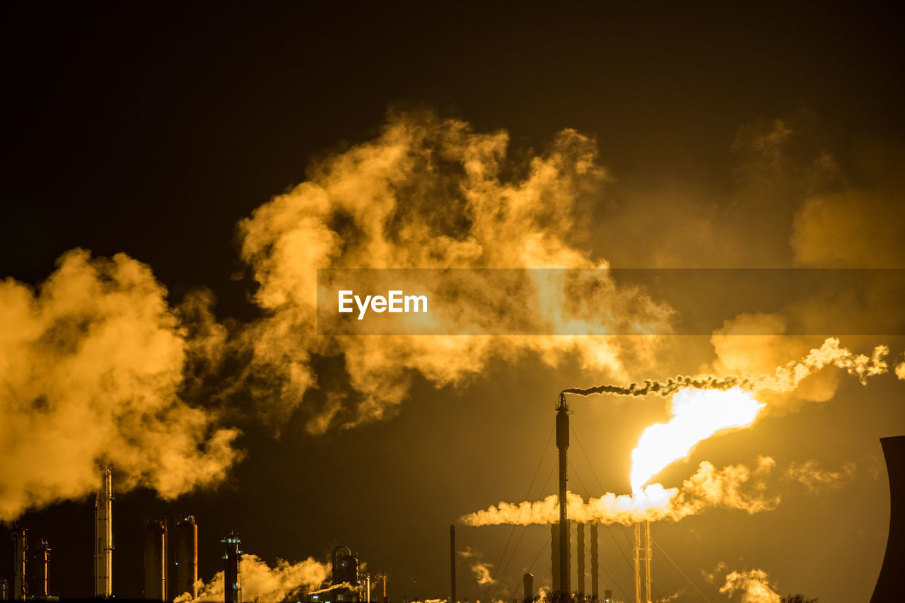 Low angle view of illuminated factory against sky at night