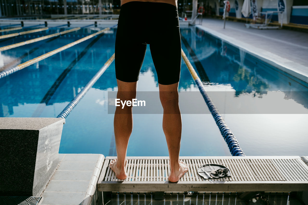 Young male swimmer standing at poolside