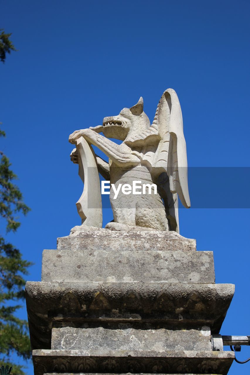 Low angle view of animal statue against clear blue sky