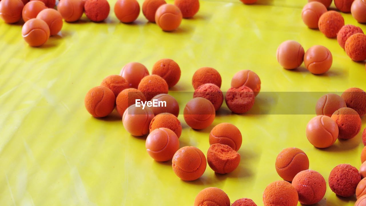 High angle view of orange balls on yellow background