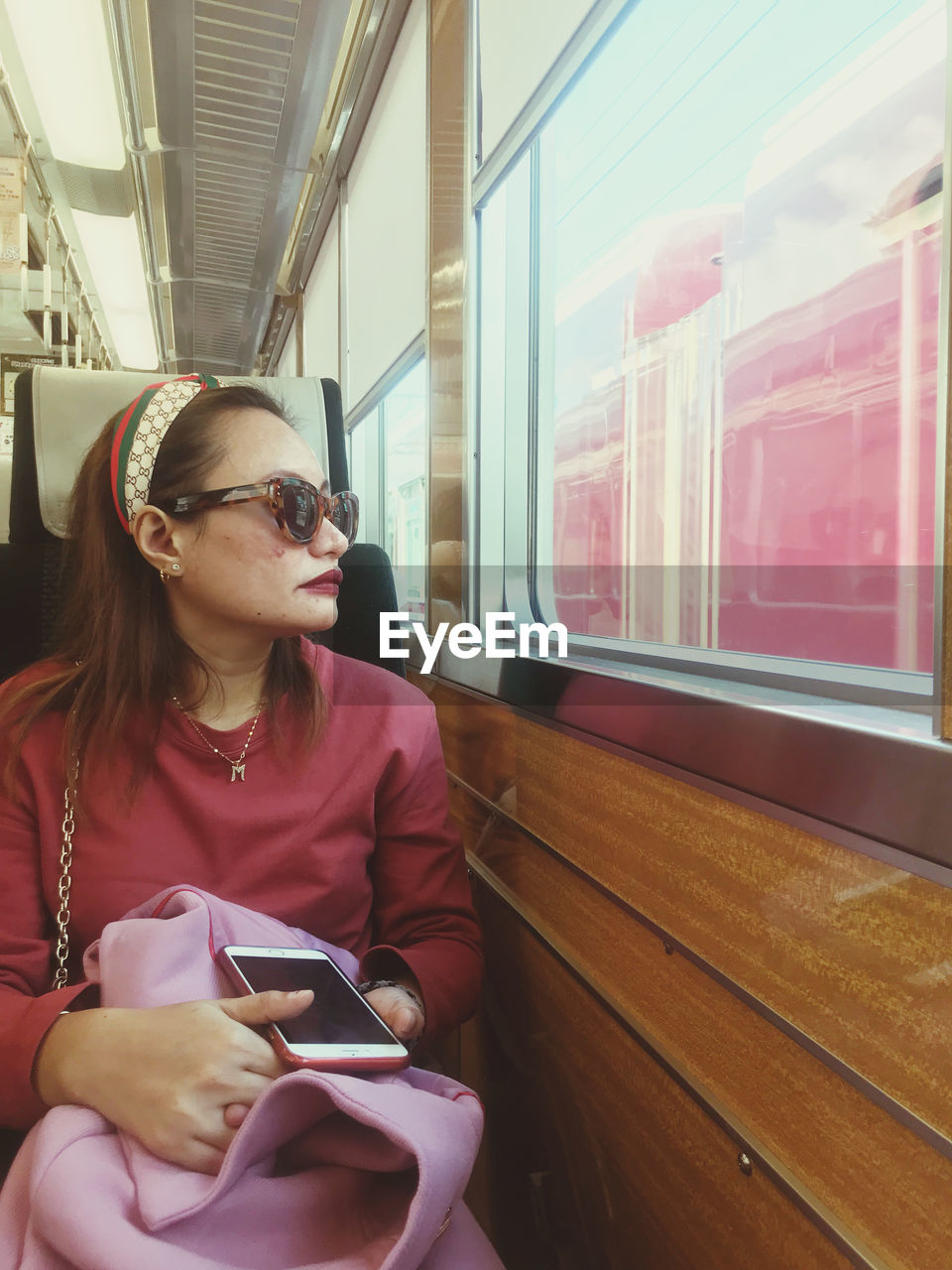 MAN USING MOBILE PHONE WHILE SITTING ON TRAIN WINDOW