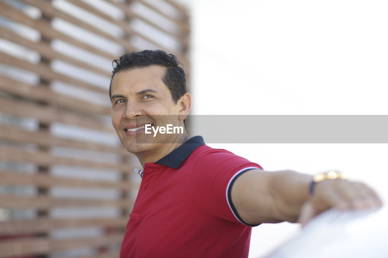 Smiling man standing by car in city