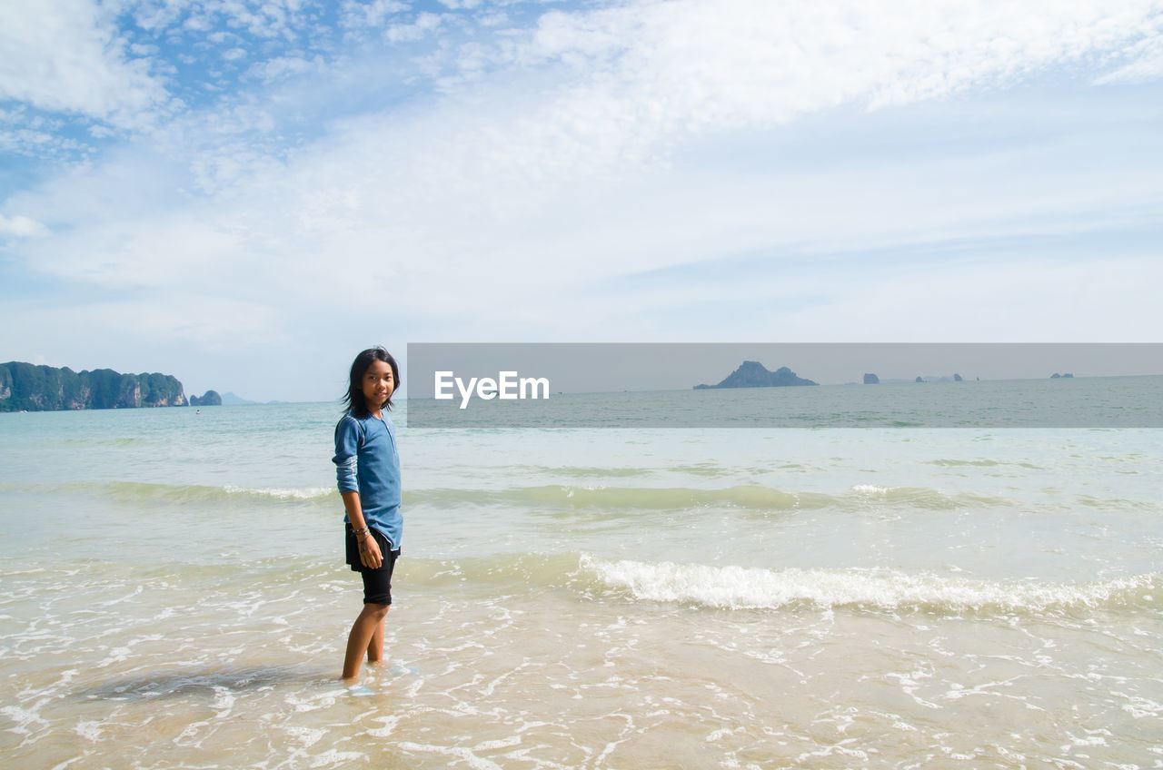 Portrait of teenage girl standing against sea at beach