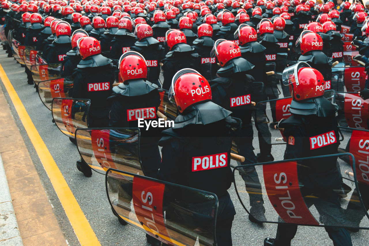 Rear view of police force marching on road in city