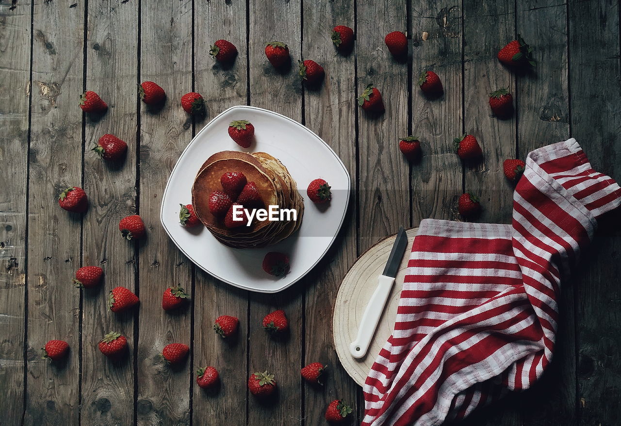 Directly above shot of strawberries with pancakes by cutting board on table