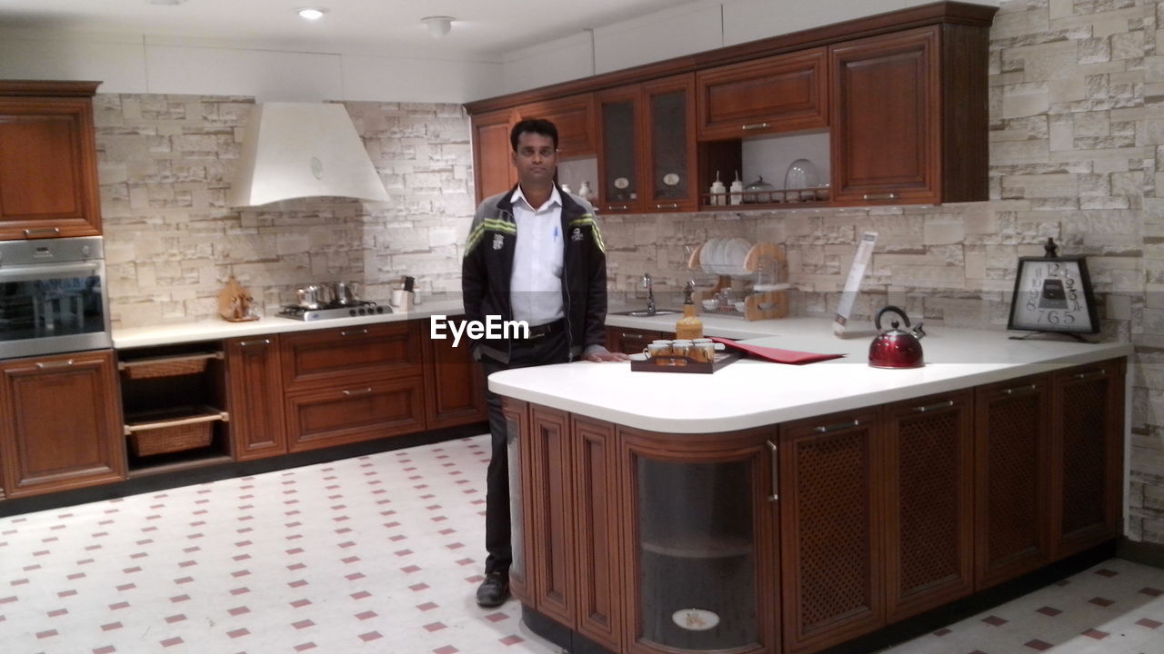 MAN STANDING IN KITCHEN