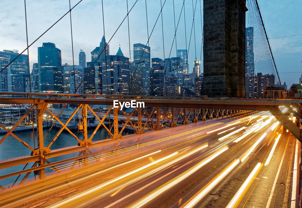 Light trails on brooklyn bridge by cityscape