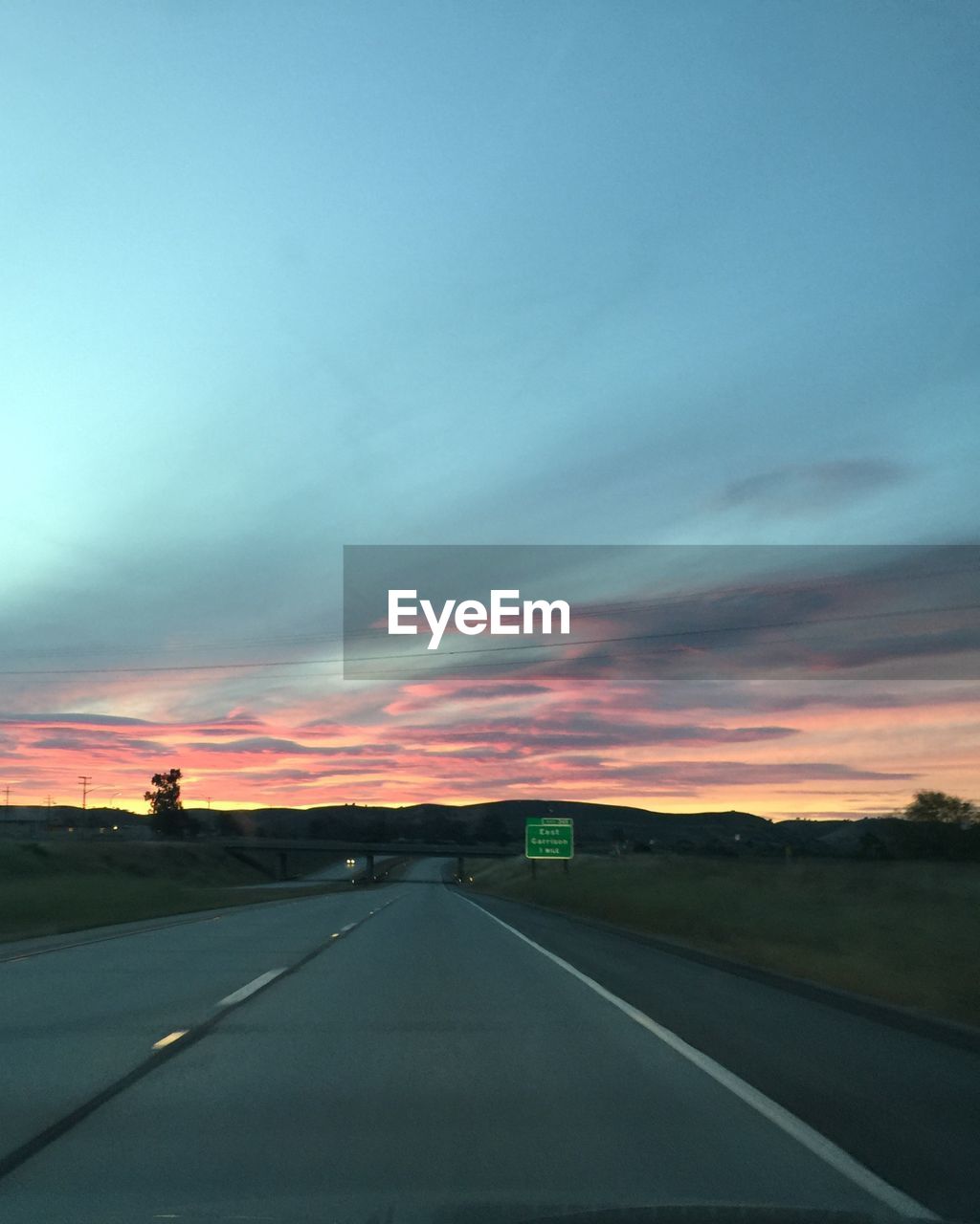 Scenic view of road against cloudy sky during sunset