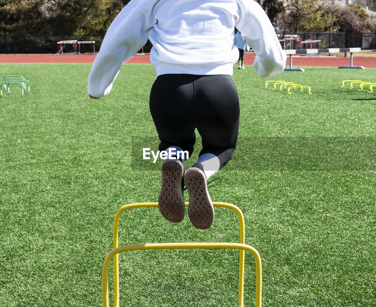 Low section of woman jumping over hurdles on turf