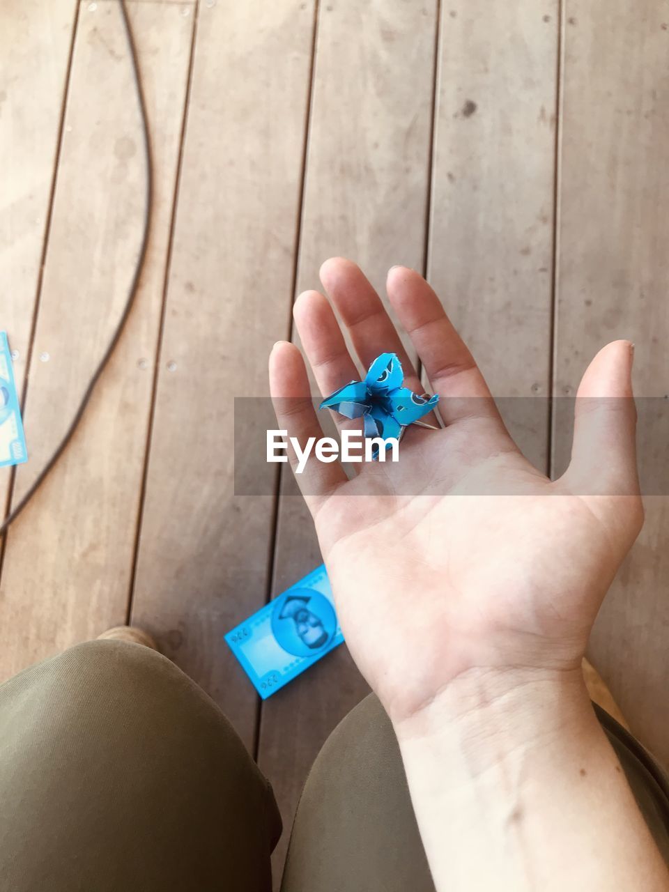 HIGH ANGLE VIEW OF HANDS HOLDING BLUE WOODEN TABLE