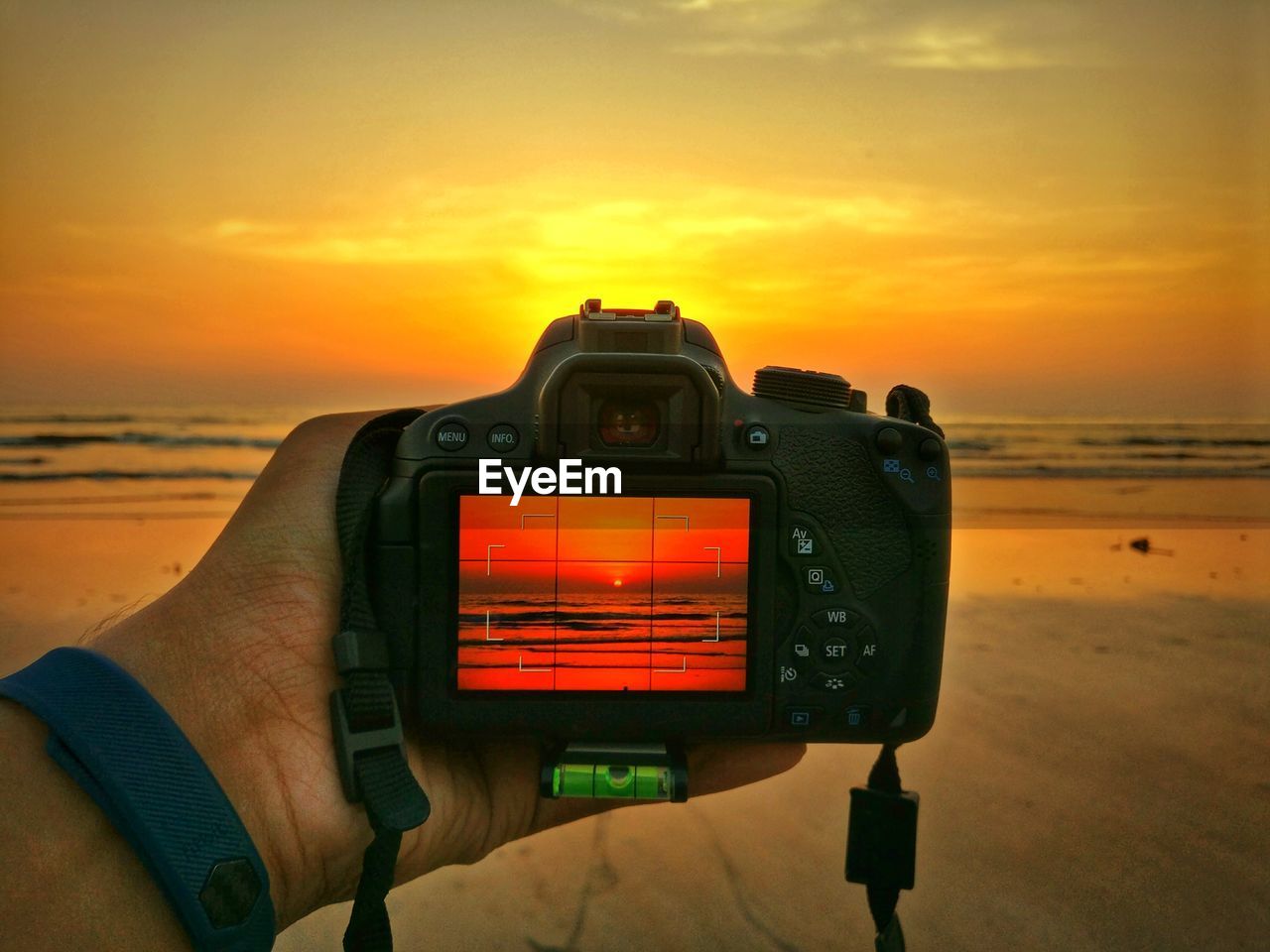 CLOSE-UP OF CAMERA ON BEACH AGAINST ROMANTIC SKY