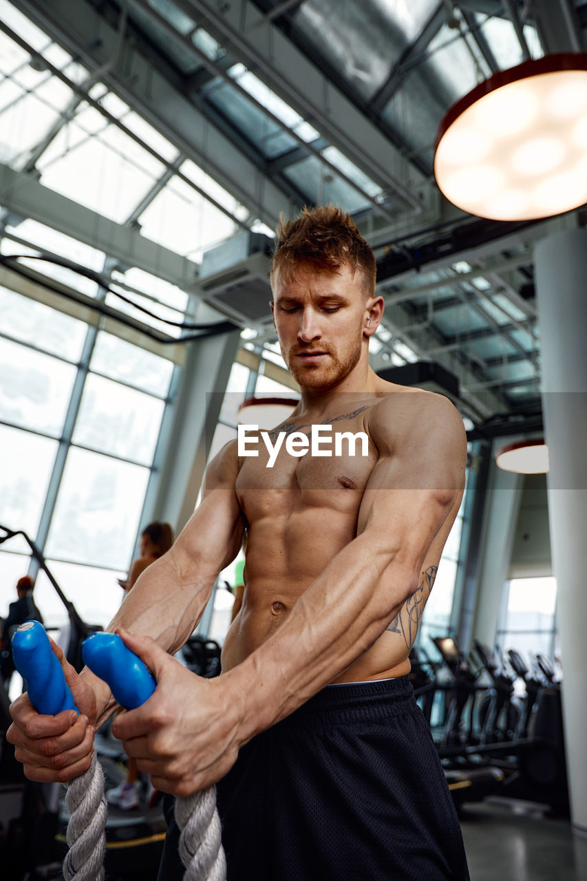 rear view of shirtless man standing in gym