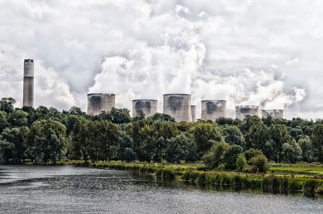 Cooling towers emitting smoke against sky