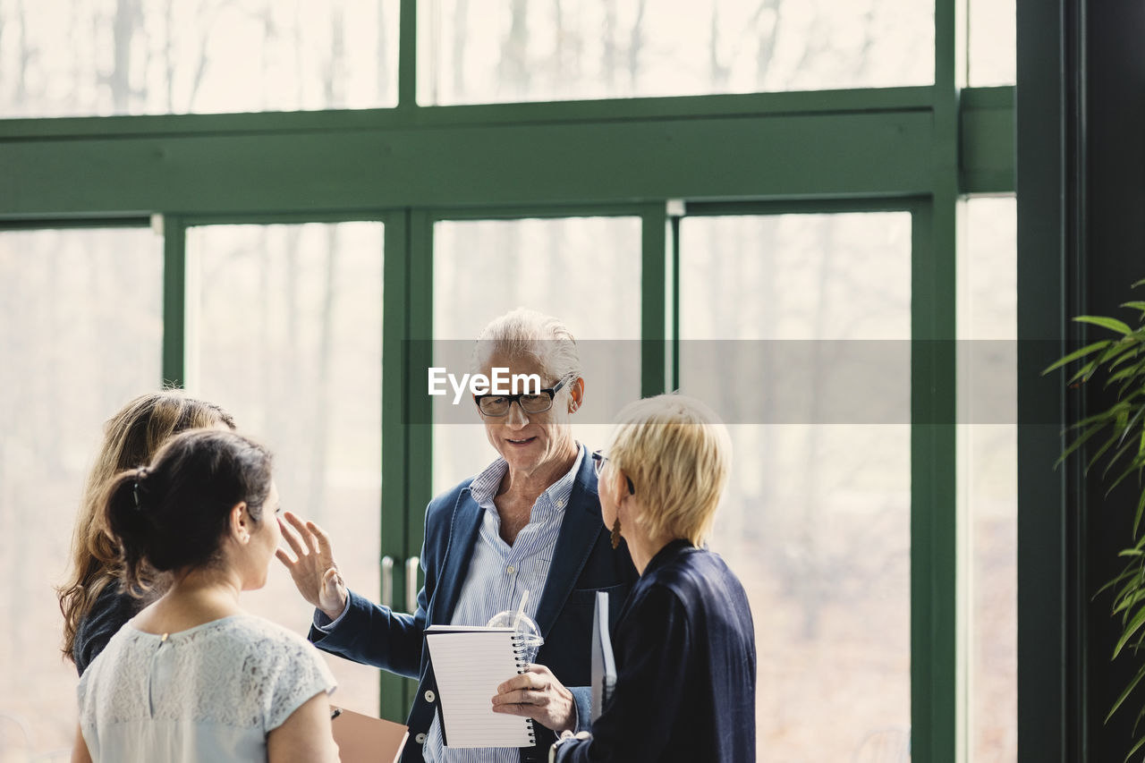 Senior businessman discussing with female colleagues in creative office