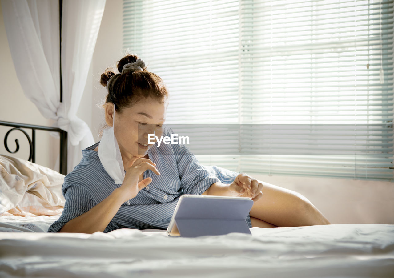 Woman looking away while sitting on bed