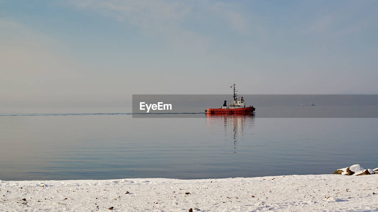 Tugboat on sea against sky.