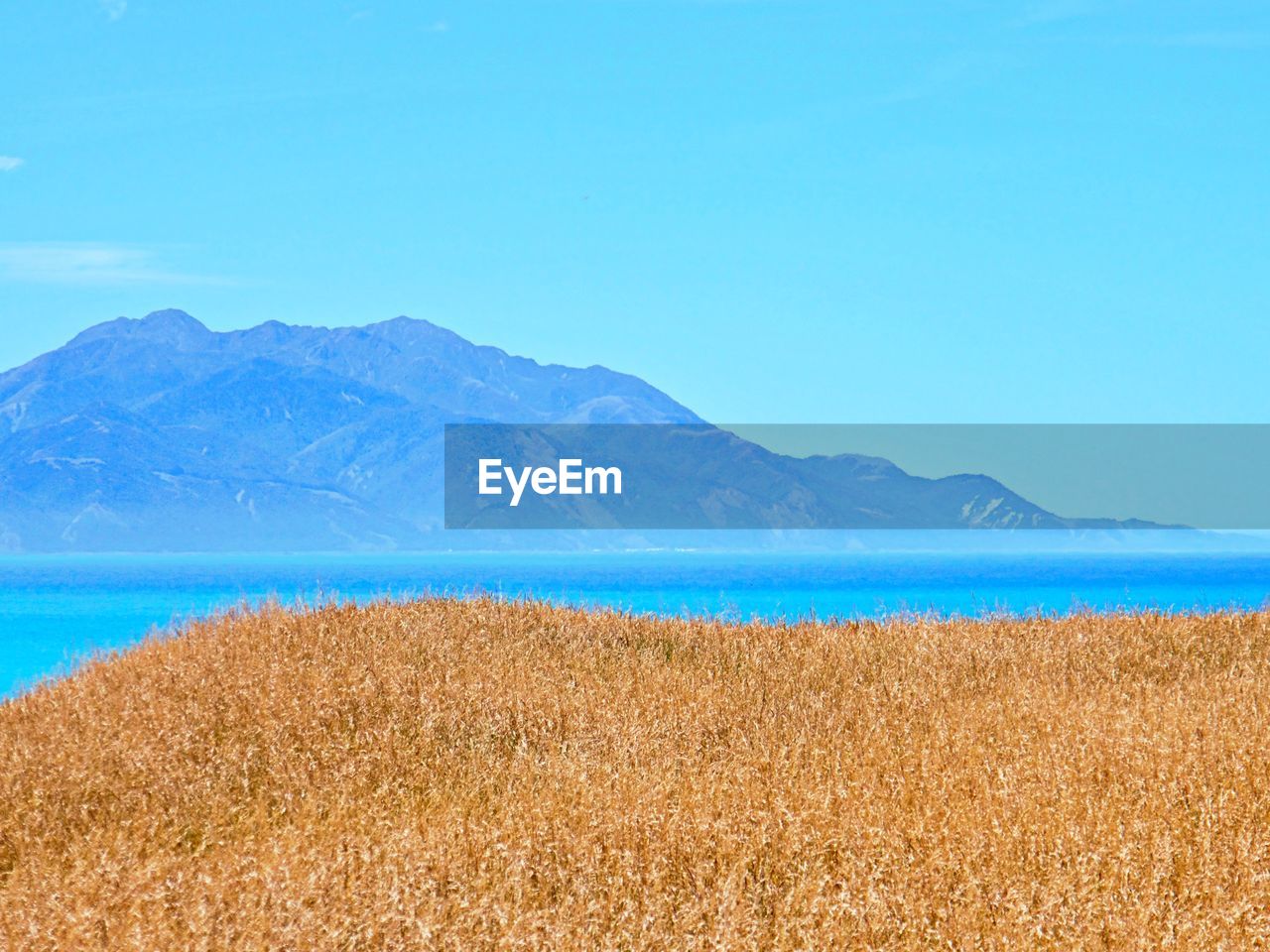 Scenic view of sea and mountains against blue sky