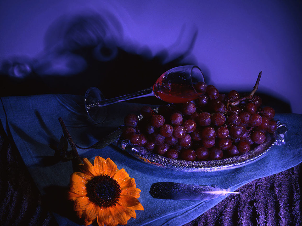 Close-up of wine glass with flowers and red grapes