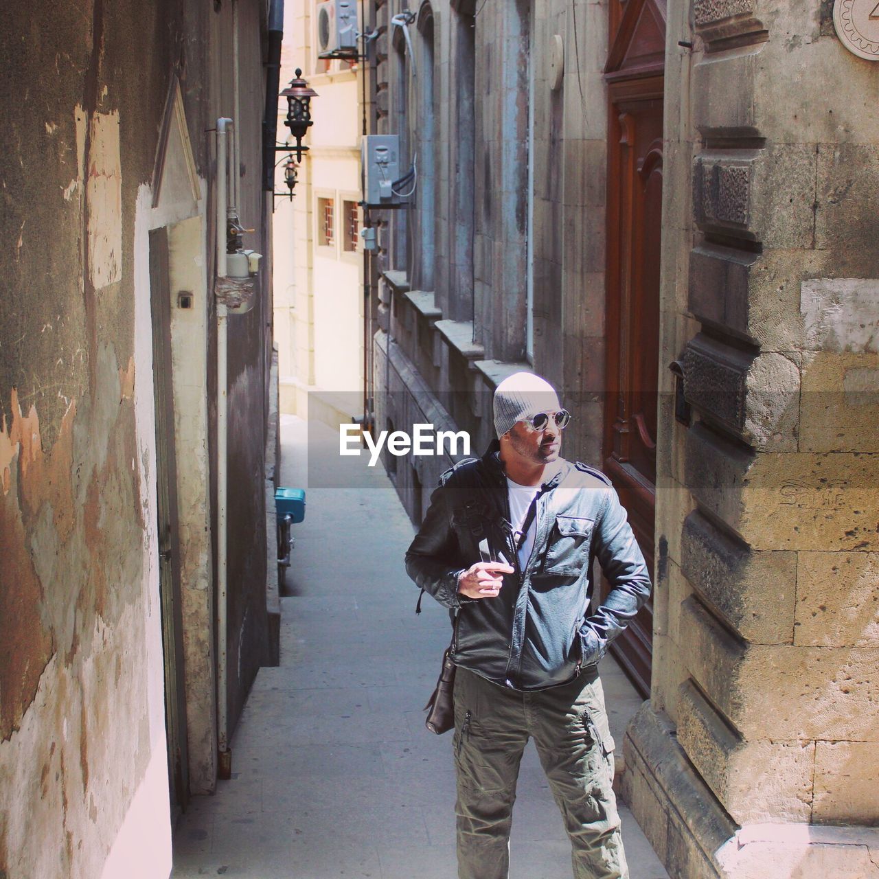 Young man standing in alley during sunny day