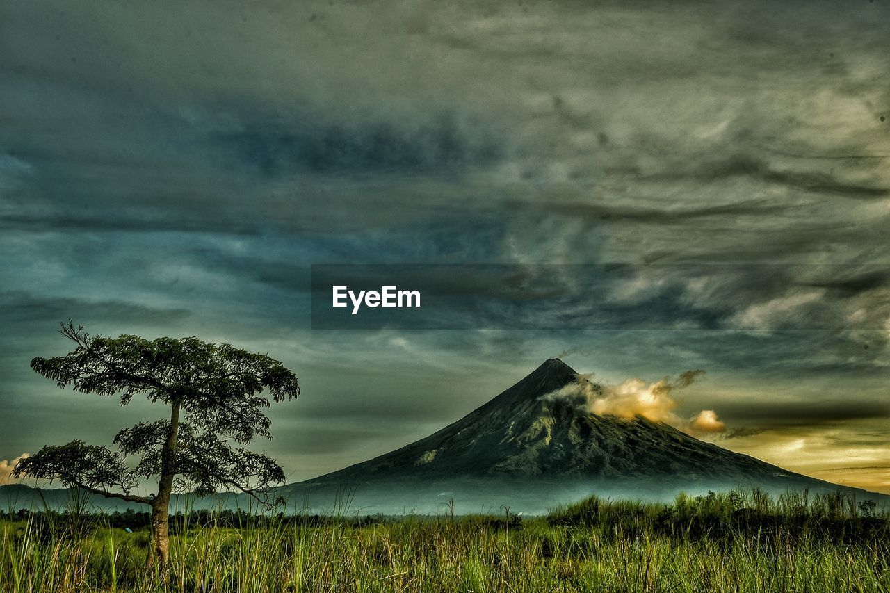 Scenic view of mountains against cloudy sky during sunset